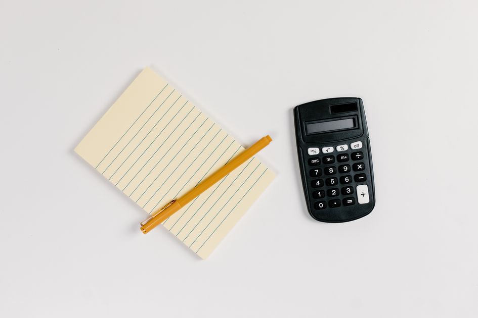 A person calculating finances with a calculator and notebook