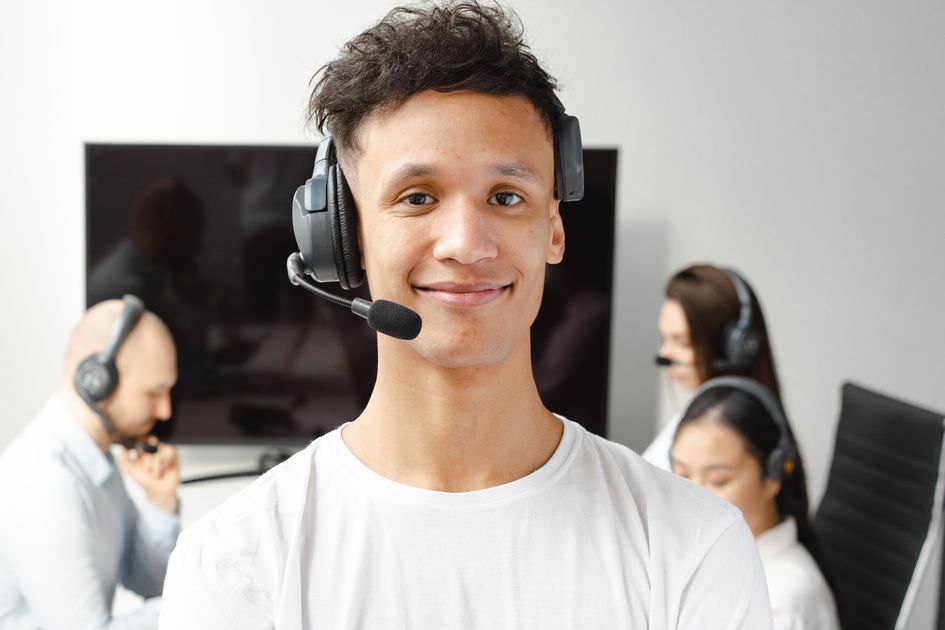 A confident call center agent wearing a headset in a bright office