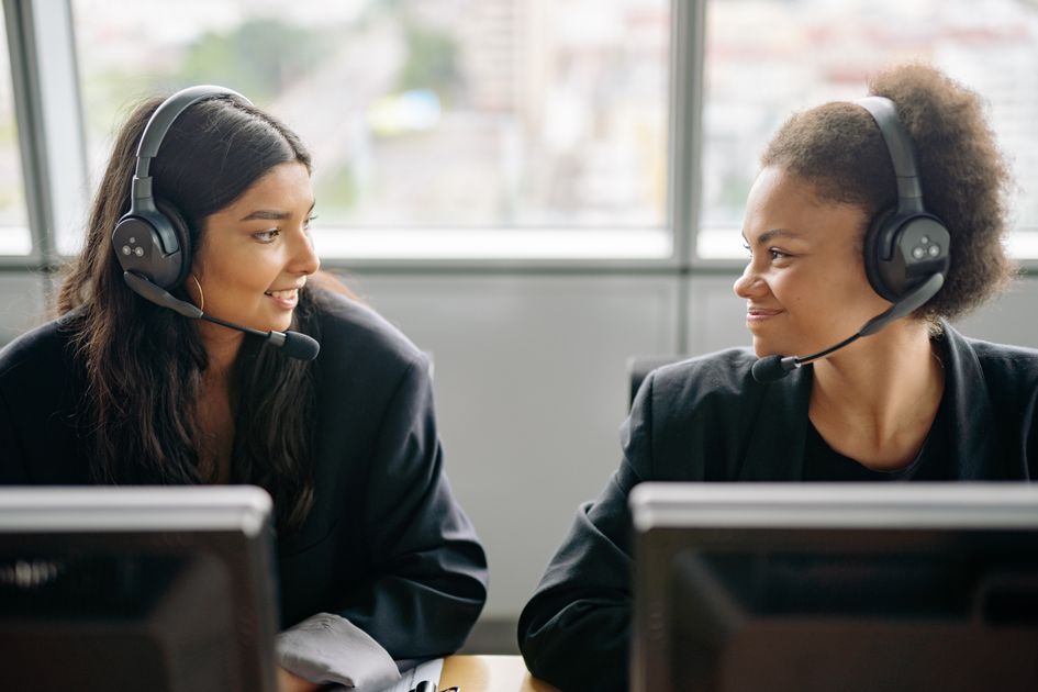 Two female agents wearing headsets working together