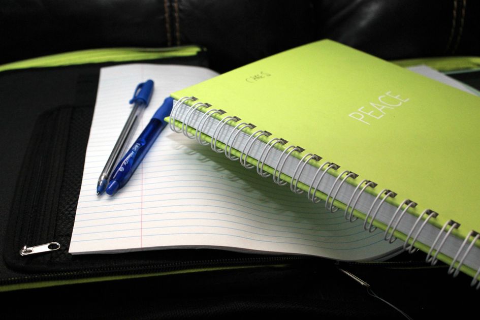 A green notebook with pens on lined paper
