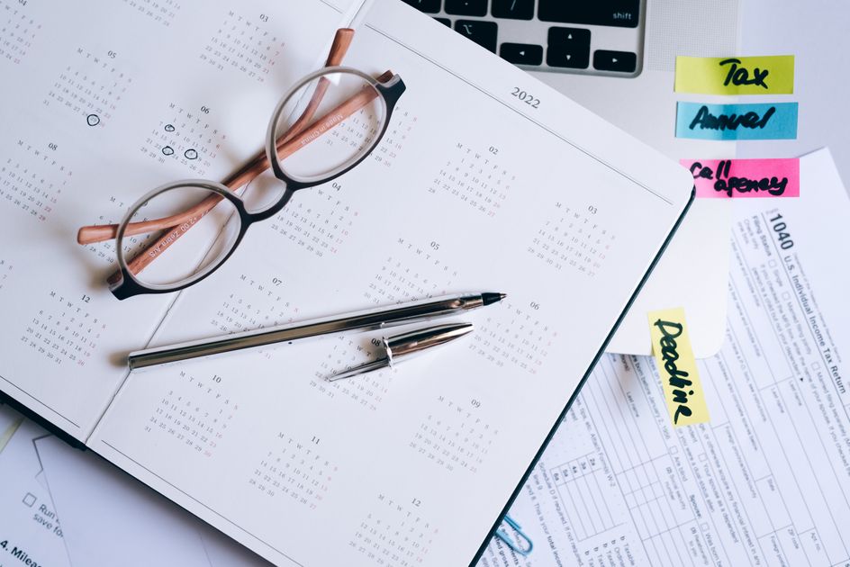 A glasses, pen and calendar arranged with documents on a desk
