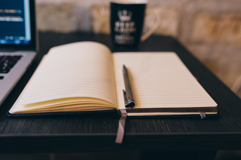 A notebook and pen on a desk for writing voice guidelines