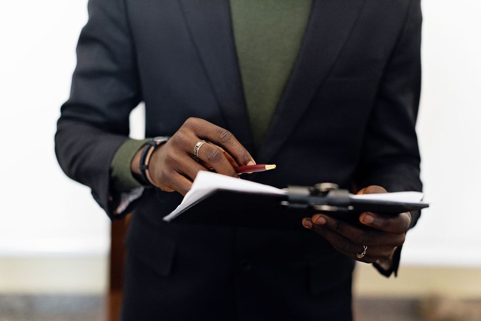 A person in a blazer holding a clipboard with documents