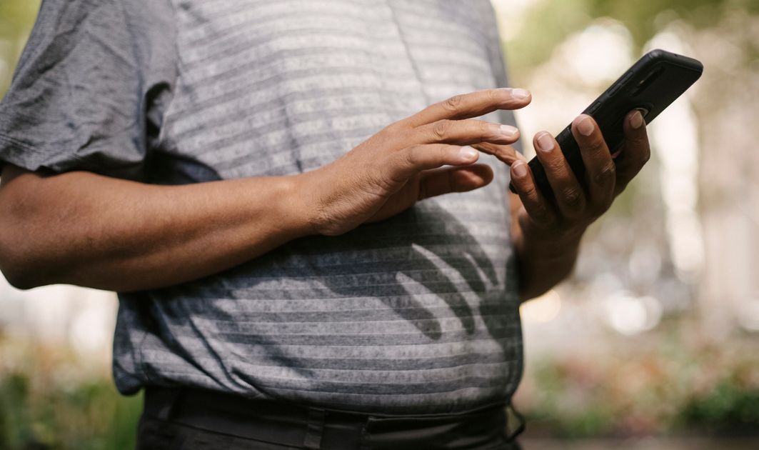 A person texting quickly on a smartphone outdoors