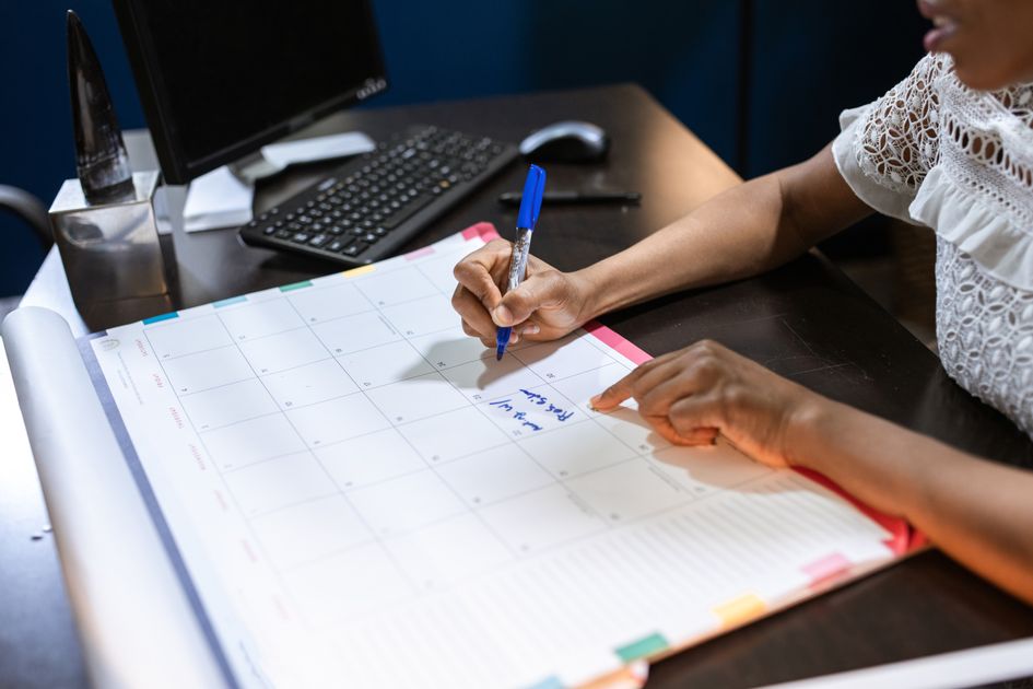 A person writing important notes in a desk calendar