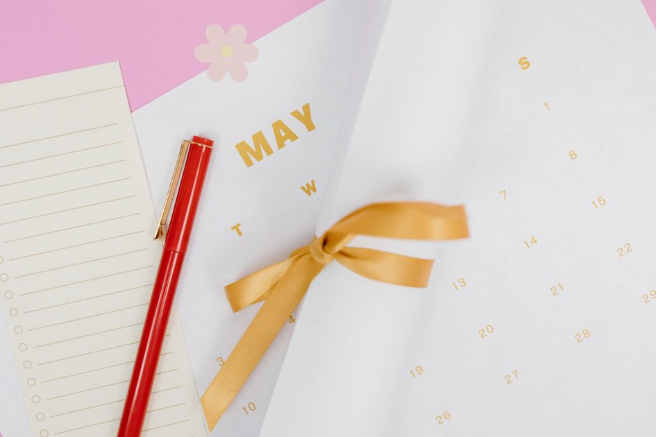A minimalist flat lay of a calendar with a red pen