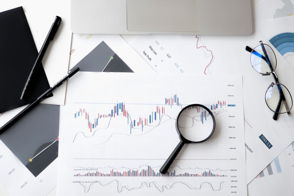 A flat lay of analysis documents with a magnifying glass and pens