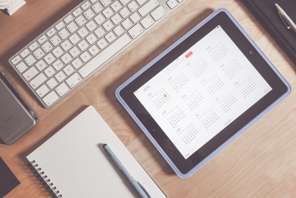 Person writing on paper calendar with important dates
