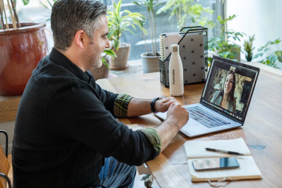 A man in a virtual meeting from his home workspace