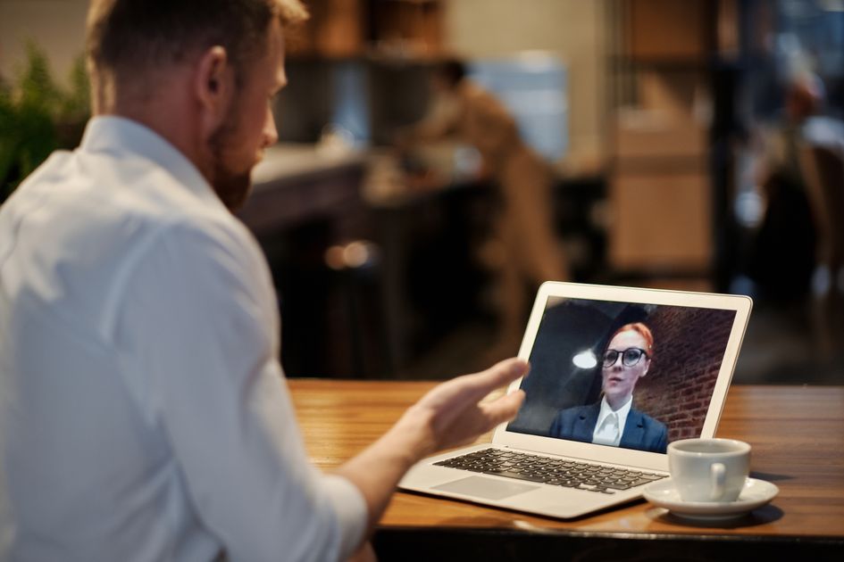 A person on a video call in a warm coffee shop setting