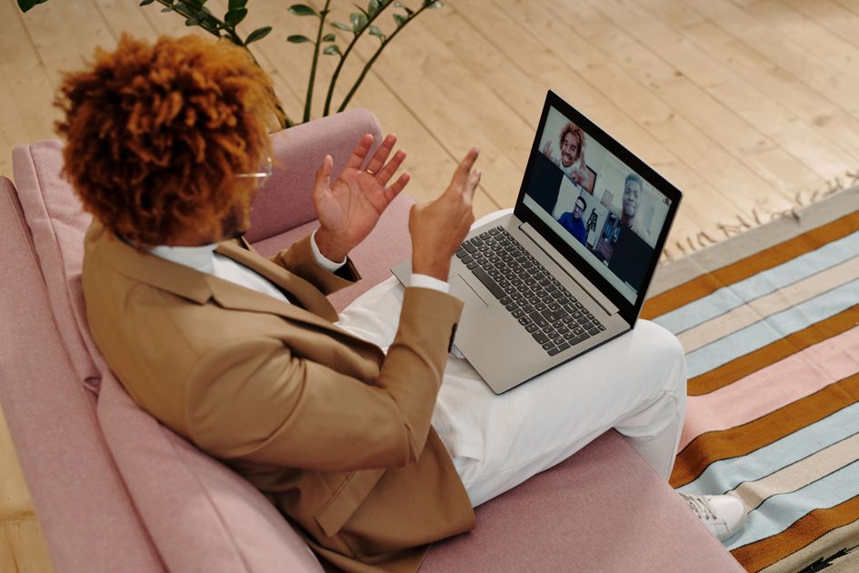 A man on a video call using a laptop while sitting on a sofa