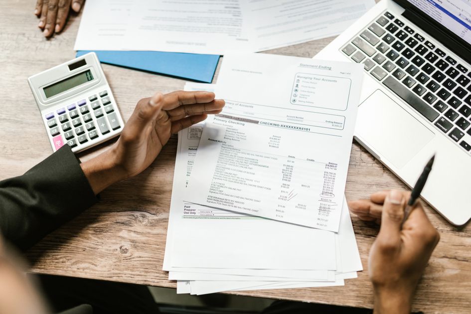 Financial documents beside a calculator and laptop on a desk