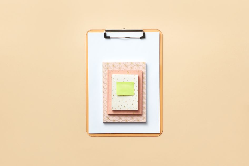 A stylish flat lay of a clipboard with notebooks and a sticky note
