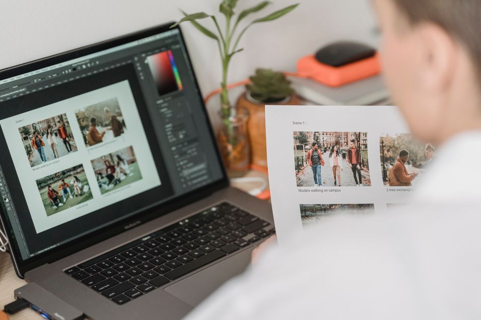 A photographer working with a laptop and printed photos