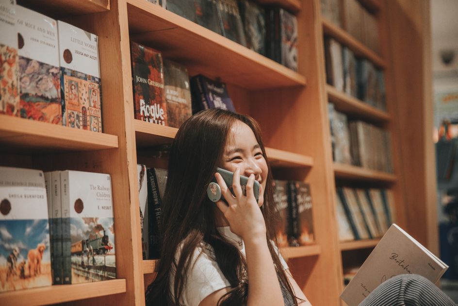 A cheerful woman speaking on her cellphone in a library