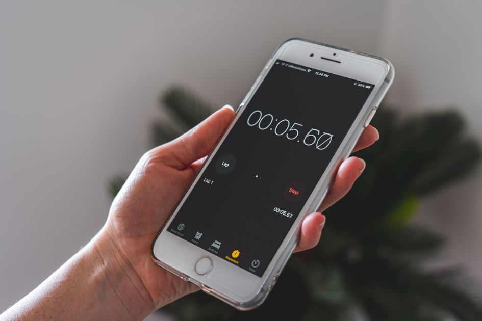 A hand holding a smartphone with a stopwatch app running