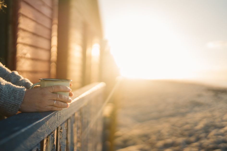 A hand holding a mug at sunrise, a quiet moment after work