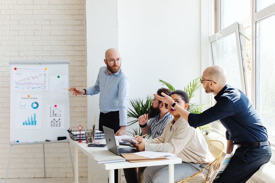 Professionals in a business meeting discussing financial graphs on a whiteboard