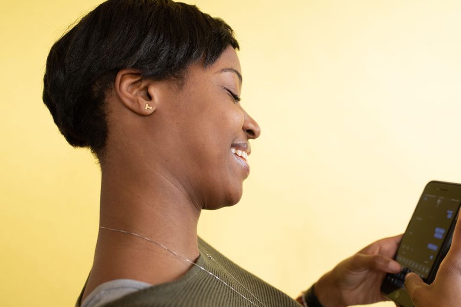 A cheerful woman texting on her smartphone against a yellow background
