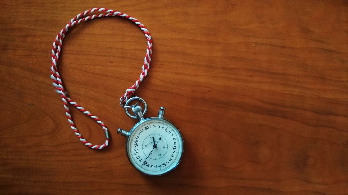 An antique stopwatch with rope on a wooden table