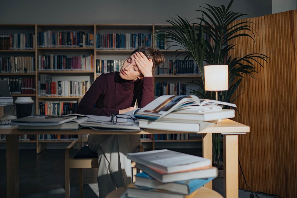 A tired person surrounded by papers, feeling decision fatigue