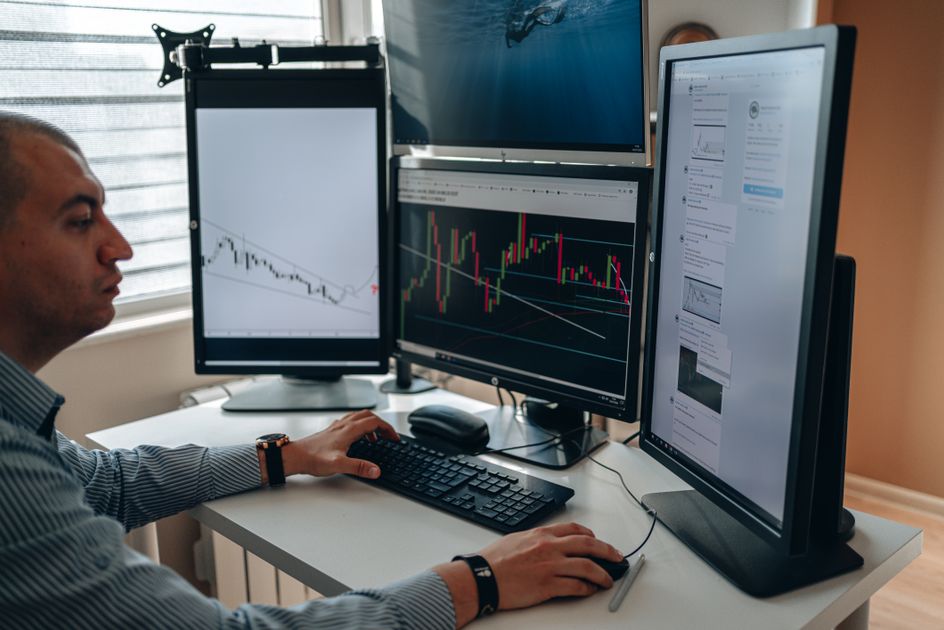 A professional analyzing charts on multiple monitors