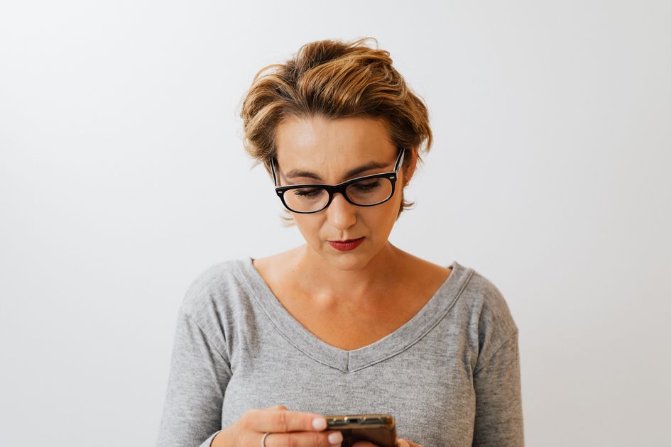 A businesswoman with eyeglasses using a smartphone indoors