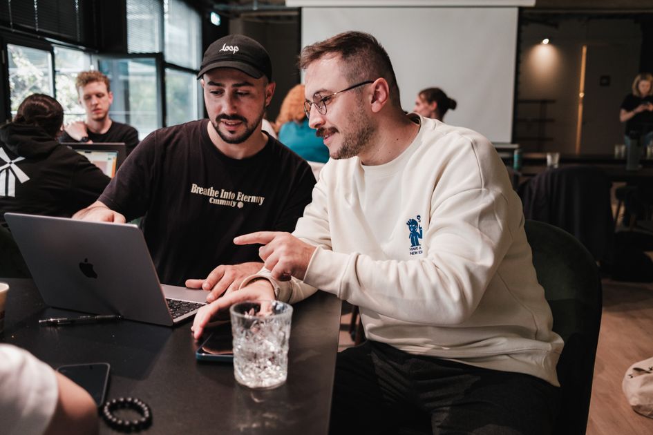 Two colleagues collaborating on a laptop in a modern cafe