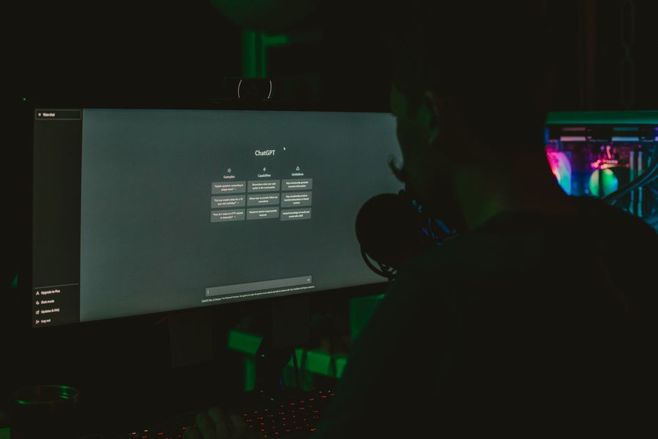 A man using a computer with a large screen in a dark room