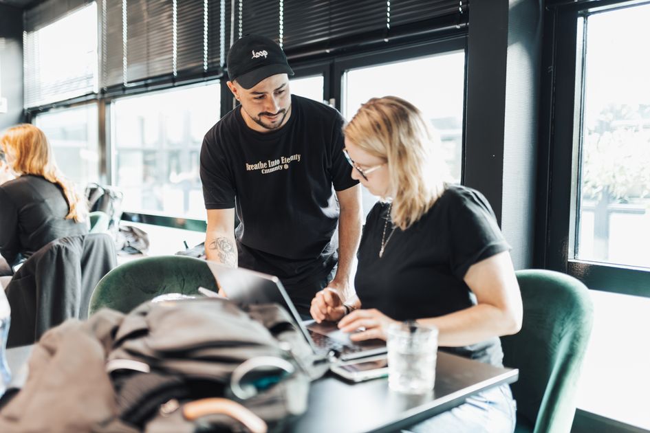 Two people collaborating in an office using a laptop