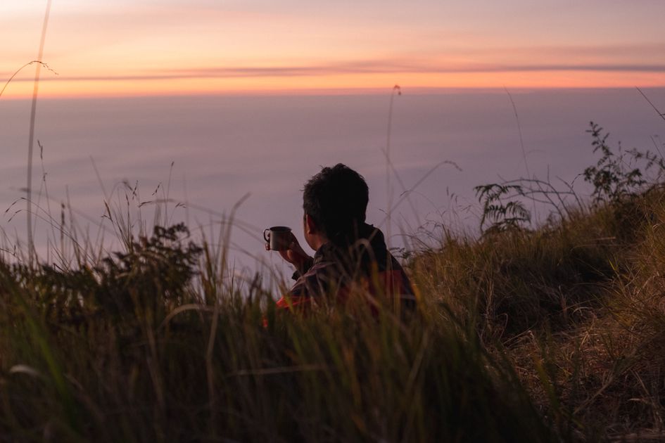 A person enjoying a calm sunrise moment on a hillside