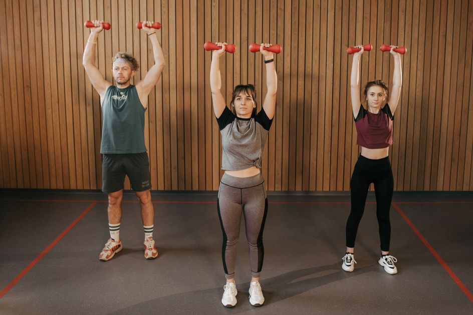 A small group exercising with dumbbells in a gym