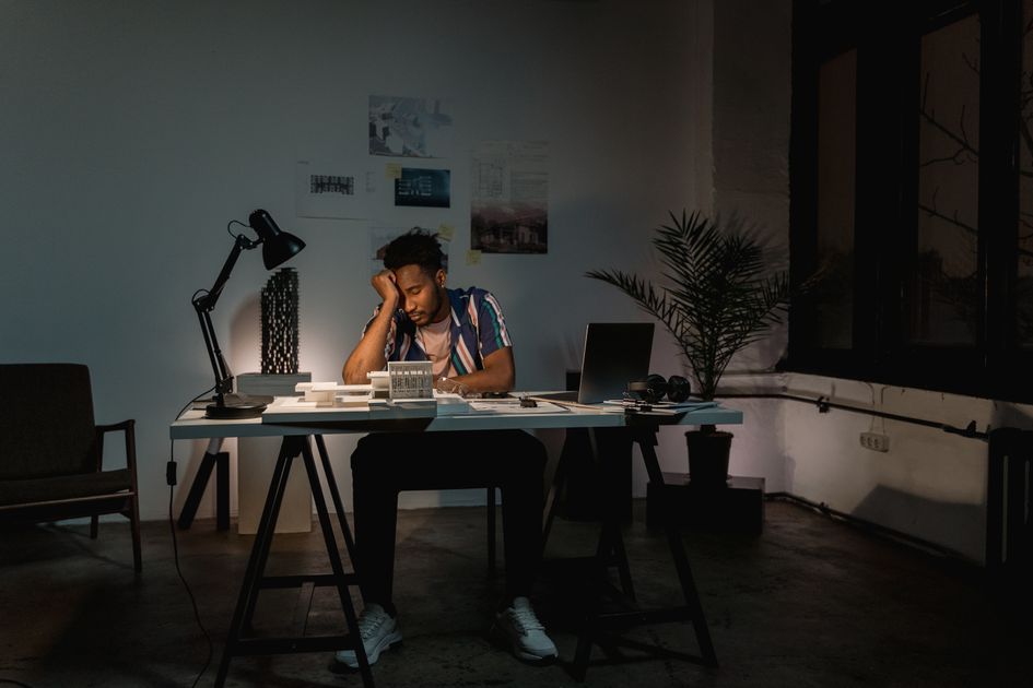 A tired professional working late by lamplight