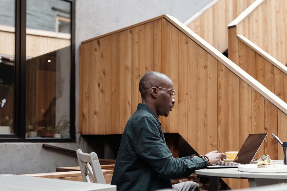 A man working remotely on a laptop in an outdoor cafe setting