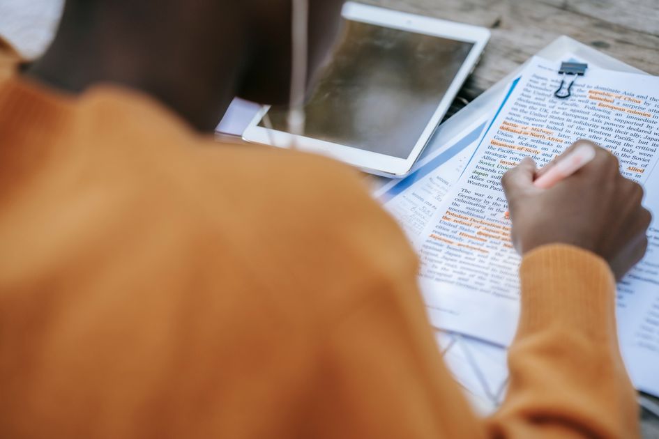 A person outlining text on a tablet at a table