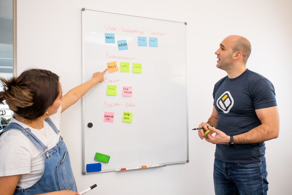 Two colleagues brainstorm on a whiteboard with colorful sticky notes