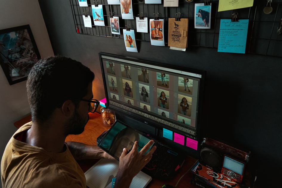 A young man editing photographs in a cozy home office