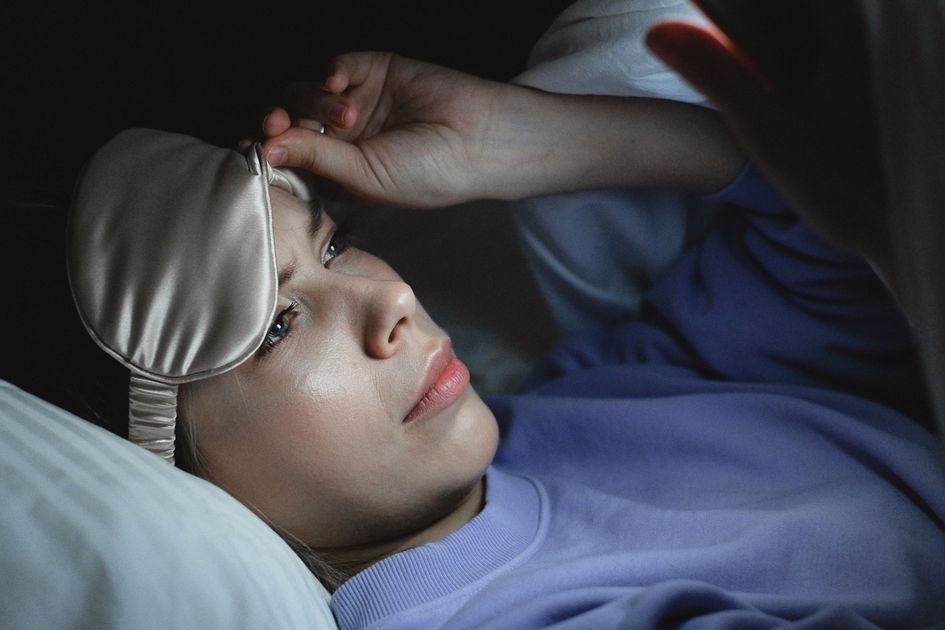 A woman peeking at her smartphone at night