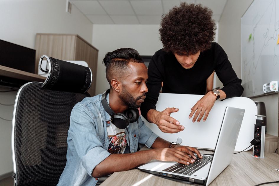 Two colleagues collaborating on a laptop in a modern office