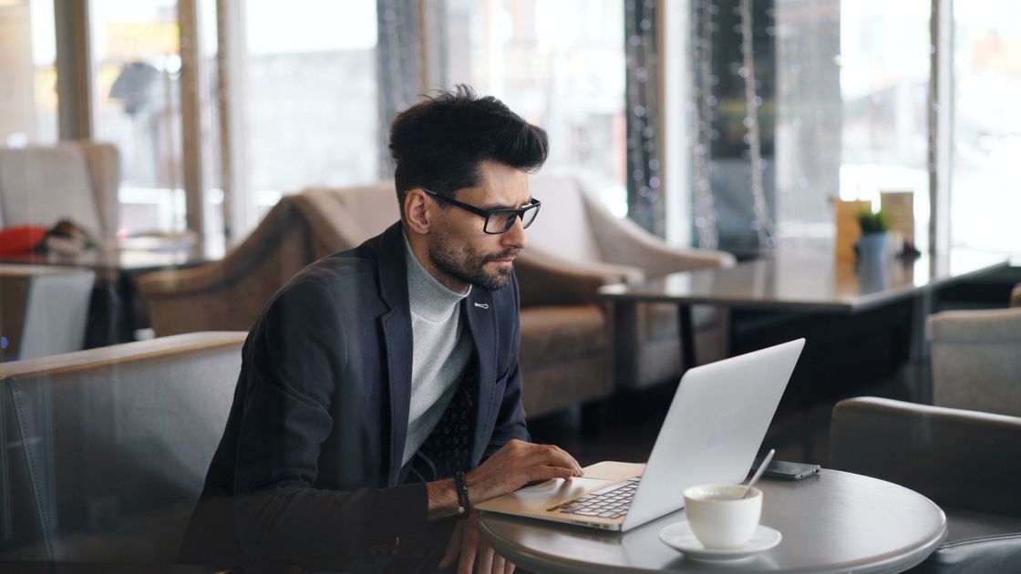 A focused businessman working on a laptop in a stylish cafe