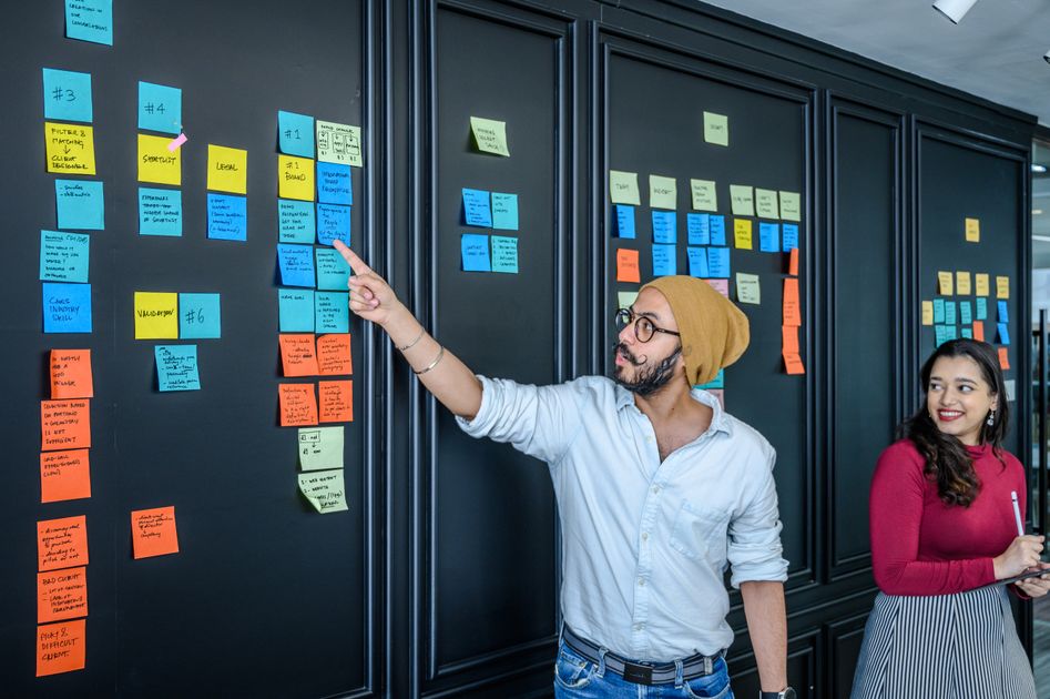 A person writing new year goals on a sticky note with a calendar