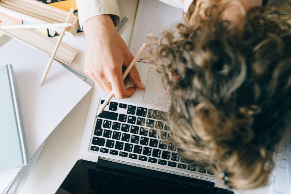 An exhausted person resting on their desk beside a laptop