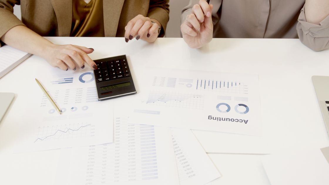 Two professionals reviewing financial figures with a calculator