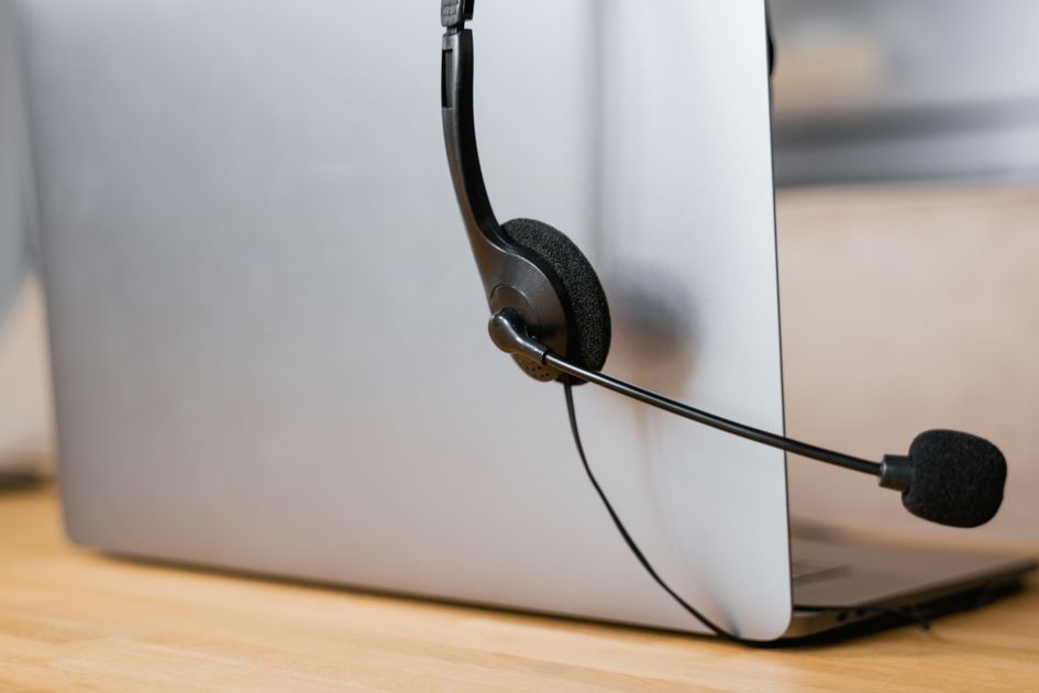 A laptop with a headset ready for a virtual assistant call