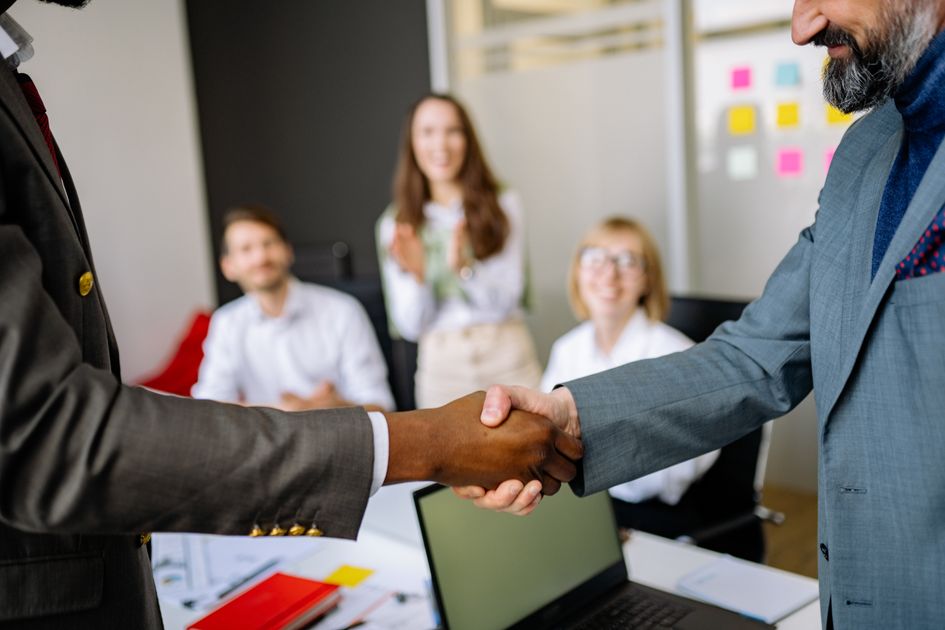 Two colleagues shaking hands to welcome a new hire