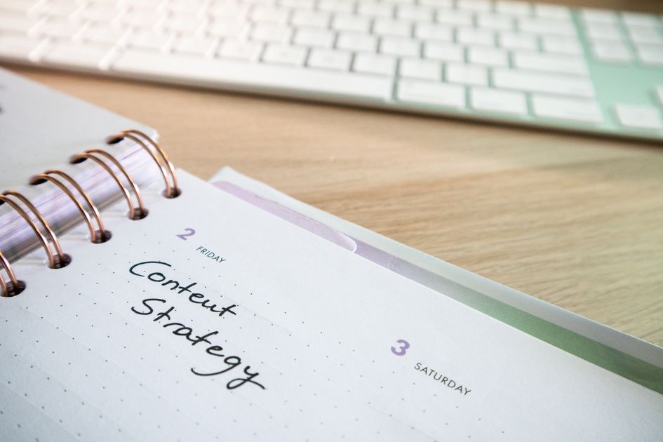 A content strategy note written in a planner beside a keyboard