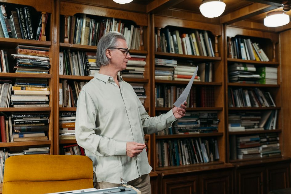 A man reading a document in a cozy library setting