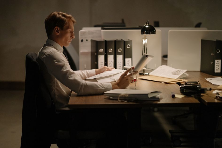 An office worker intensely focused while reading documents at a desk