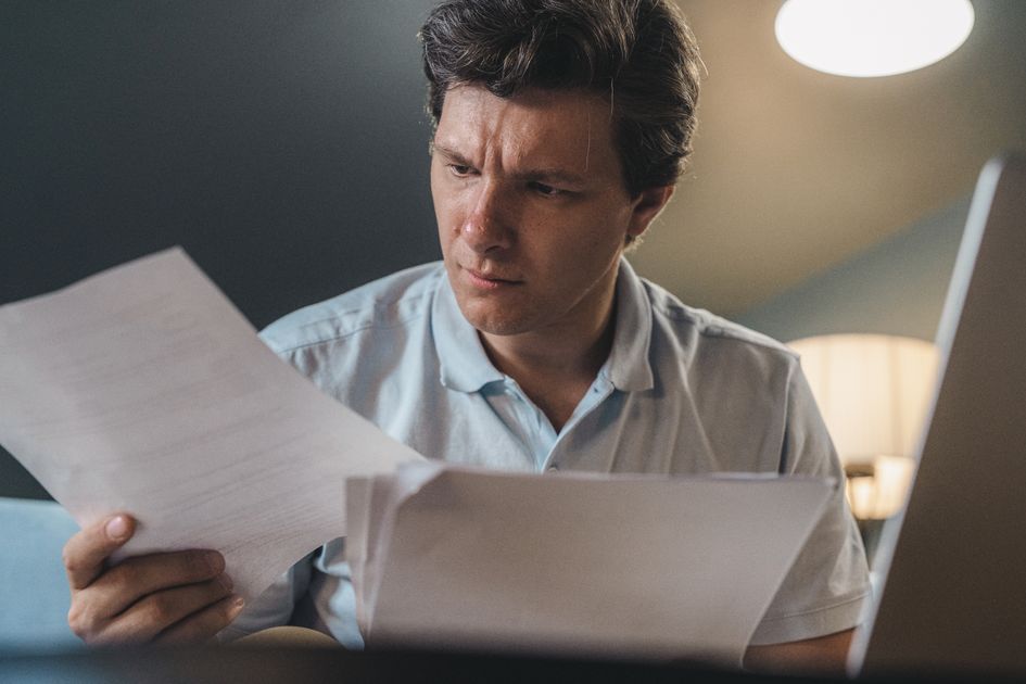 A man intently examining papers under warm lighting