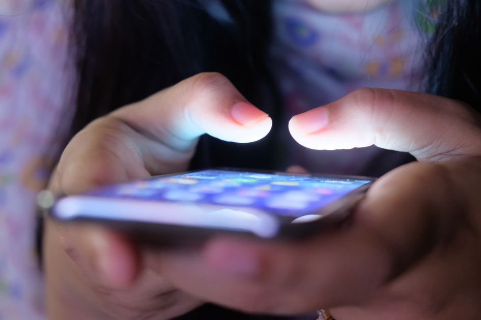 Hands holding a smartphone with a glowing screen